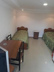 a room with two beds and a table and a television at NarVar Hotel in Goris