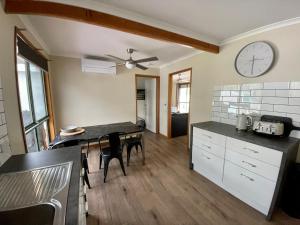 a kitchen with a table and a clock on the wall at Vacation on Nation in Inverloch