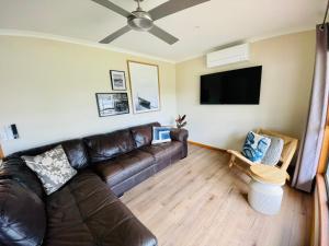 a living room with a leather couch and a flat screen tv at Vacation on Nation in Inverloch