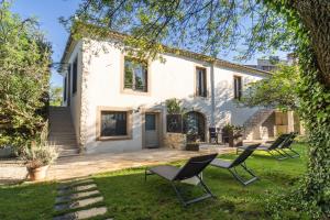 a white house with chairs in the yard at Chambre d'hôte avec SPA privatif domaine les nuits envôutées - Gard in Vézénobres