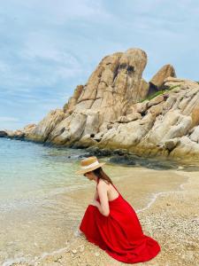 a woman in a red dress sitting on the beach at Yen Vang Hotel & Apartment Nha Trang in Nha Trang