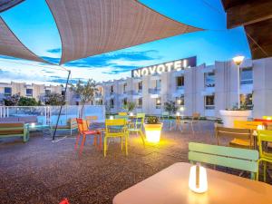 eine Terrasse mit bunten Tischen und Stühlen vor einem Hotel in der Unterkunft Novotel Perpignan Nord Rivesaltes in Rivesaltes