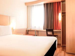 Habitación de hotel con cama, escritorio y ventana en ibis Lille Centre Gares, en Lille