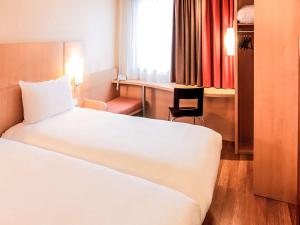um quarto de hotel com uma cama branca e uma secretária em ibis Lille Centre Gares em Lille