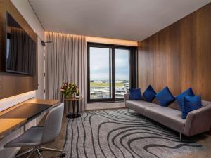 a living room with a couch and a large window at Novotel Christchurch Airport in Christchurch