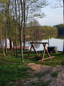 a picnic table on the side of a lake at Pelakys Glamping Lounge in Šlepečiai