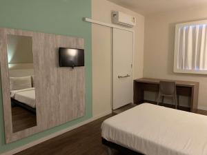 a bedroom with a mirror and a bed and a desk at ibis budget Muriae in Muriaé