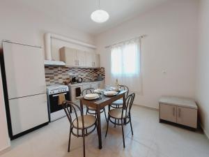 una cucina con tavolo, sedie e frigorifero bianco di Stamatis Corfu Apartment 2 a Ipsos