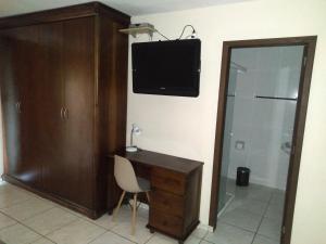 a room with a desk and a television on a wall at Pousada Praia do Calixto in São Francisco do Sul