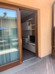 une porte coulissante en verre menant à une chambre avec une cuisine. dans l'établissement Appartamento IRIS, à Spinone Al Lago
