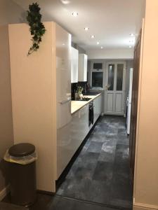 a kitchen with white cabinets and a trash can at Ainsdale Gardens in Birmingham
