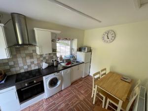 a kitchen with a table and a clock on the wall at Cosy 2 Bedroom Cottage in Betws y Coed, Snowdonia in Betws-y-coed