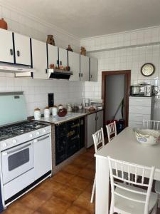 una cocina con electrodomésticos blancos y una mesa con sillas. en CASA OROSITA, en Finisterre