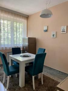a dining room with a white table and blue chairs at City Place Apartments in Kumanovo
