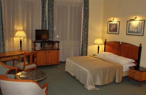 a hotel room with a bed and a desk and a television at Hotel Centrál in Nagykanizsa