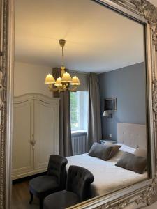a mirror in a bedroom with a bed and a chair at Le Domaine De Pairis in Orbey