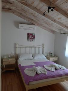 een slaapkamer met een groot bed met paarse lakens bij kedros in Elafonisos