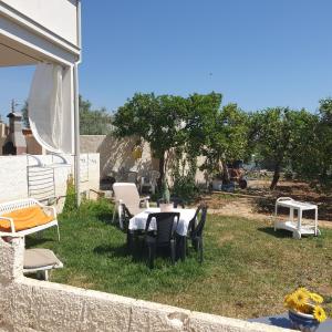 een patio met een tafel en stoelen in het gras bij villetta immersa nell'agrumeto in Noto Marina