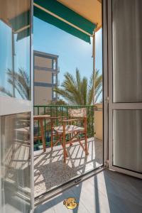 an open glass door with a chair on a balcony at Pesce Palla Affittacamere in Finale Ligure