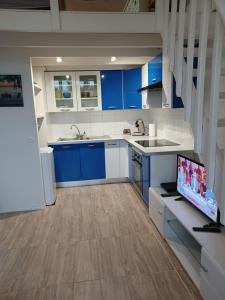 een keuken met blauwe kasten en een flatscreen-tv bij Résidence MARINA 3 in Les Trois-Îlets