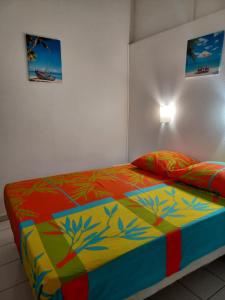 a bedroom with a bed with a colorful blanket at Résidence MARINA 3 in Les Trois-Îlets
