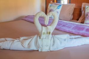 two towels shaped like swans sitting on a bed at The Nest House in Pai