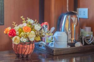 a vase of flowers on a counter with a coffee pot at The Nest House in Pai