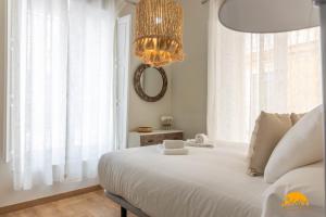- une chambre avec un grand lit blanc et un lustre dans l'établissement Carpenter's Home by Cadiz Time, à Cadix