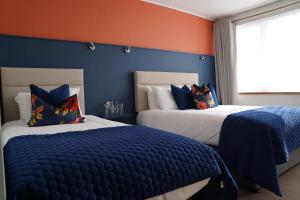2 letti in una camera da letto con pareti blu e arancioni di Alcock & Brown Hotel a Clifden