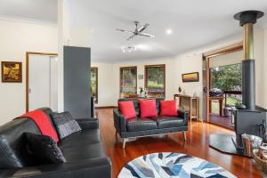 a living room with a black leather couch and red pillows at Ravensbourne Escape-Tree Tops in Ravensbourne