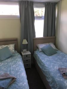 two beds in a small bedroom with a window at Pine Song Chalet in Roch