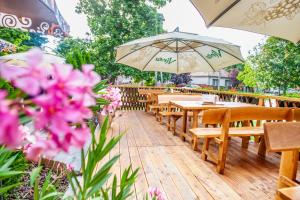 eine Reihe von Tischen und Sonnenschirmen auf einer Terrasse mit rosa Blumen in der Unterkunft Penzión Tücsök in Šamorín