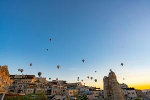 un groupe de montgolfières survolant une ville dans l'établissement Century Cave Hotel, à Gorëme