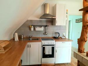 a kitchen with white cabinets and a sink and a stove at Bonnys Ferienwohnung in Nohfelden