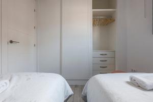 a white bedroom with two beds and a closet at Family HOME SUITS Encantos de Sevilla in Seville