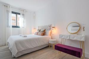 biała sypialnia z dużym łóżkiem i lustrem w obiekcie Family HOME SUITS Encantos de Sevilla w Sewilli