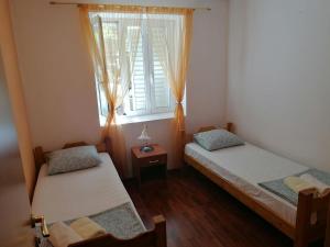 two twin beds in a room with a window at Apartmani Ljumović Budva in Budva