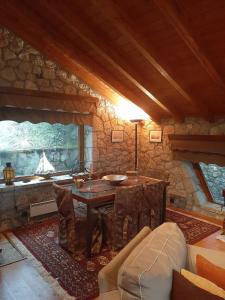 a living room with a table and a stone wall at Mouses Chalet Lydia Επτάλοφος Παρνασσού in Eptalofos