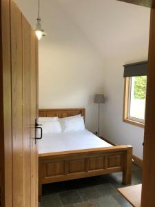 Schlafzimmer mit einem Bett mit einem Holzrahmen und einem Fenster in der Unterkunft The Cottage, near Glasgow Milngavie in Milngavie