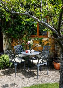 a table and two chairs and a table with flowers on it at Cosy cottage Blockley, Cotswolds - Squire Cottage in Blockley