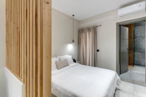 a bedroom with a white bed and a window at Argento urban apartments (cube) in Ermoupoli