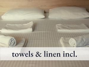 two beds with pillows and towels and the words towels and linear inn at Tolle Zweiraum-Ferienwohnung in bester Lage l Innenstadtnähe l 1 Minute zum Bahnhof l TV l Free-WLAN l Keine Küche l Willkommen im Hallo!-Apartment 4 in Bad Wörishofen