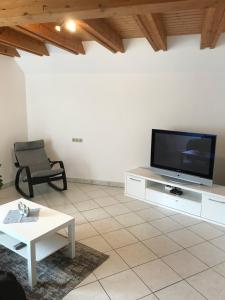 a living room with a flat screen tv and a chair at DZ im Haus Maja in Holzkirchen