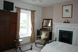a bedroom with a bed and a chair and a fireplace at Penralley House B&B in Rhayader