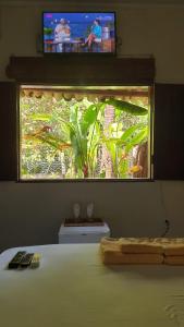 a bedroom with a window with a television above a bed at Casa Antiga Hospedagem - Taipu de Fora in Barra Grande