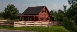 a small red house with a fence in a field at Dobre Miejsce na Roztoczu in Huta Różaniecka