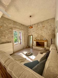 - un salon avec un canapé et un mur en pierre dans l'établissement Πέτρινο σπίτι με κήπο και θέα στον ελαιώνα, Katouna Home II, à Katouna