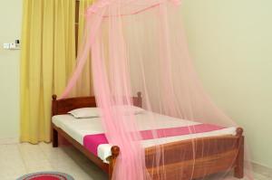 a bed with a pink canopy in a room at Tissa Resort in Tissamaharama