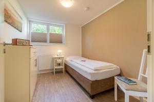 ein kleines Schlafzimmer mit einem Bett und einem Tisch in der Unterkunft Gästehaus Wohnung 2 in Wyk auf Föhr