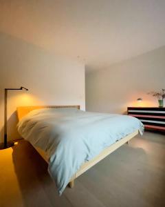 a bedroom with a white bed in a room at Huis van Hout - architectenwoning met grote panorama tuin - design hot tub optioneel in Herk-de-Stad